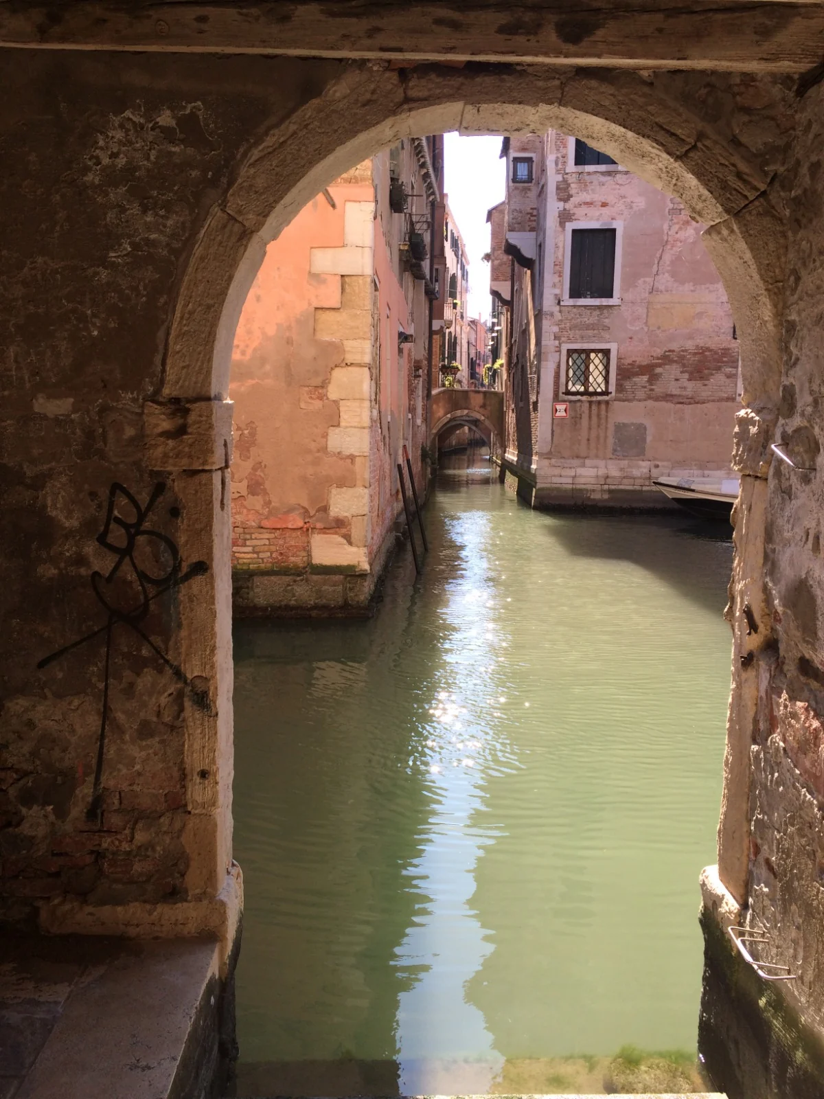 Canal seen through a brick archway in Venice